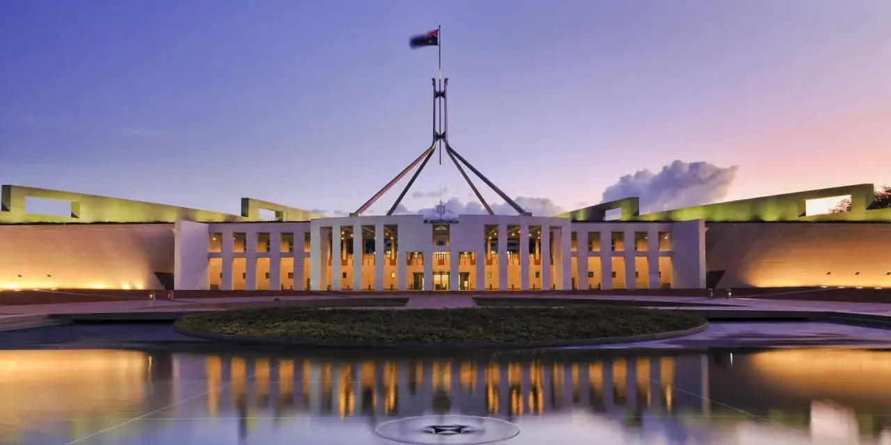 Das Parlamentsgebäude, die Hauptstadt Australiens, im Abendlicht mit reflektierendem Wasserbecken.