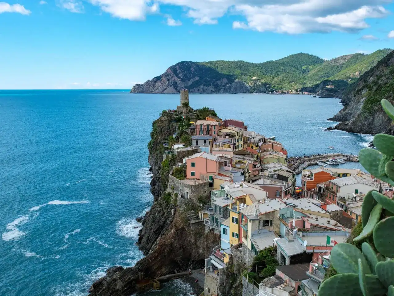 Bunte Häuser kleben an steilen Klippen am Meer. Ein perfekter Urlaub in Italien, mit Blick auf das azurblaue Meer und die Berge.