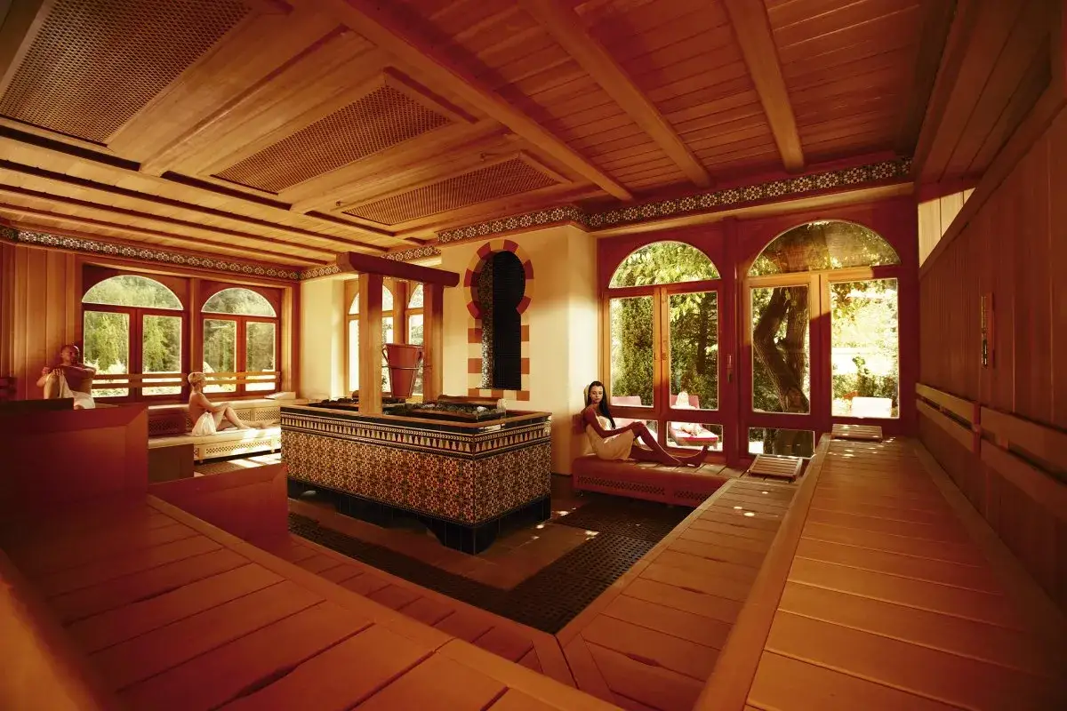 Entspannung pur im sieben welten hotel & spa resort. Frauen genie&szlig;en die Sauna mit Blick ins Gr&uuml;ne.