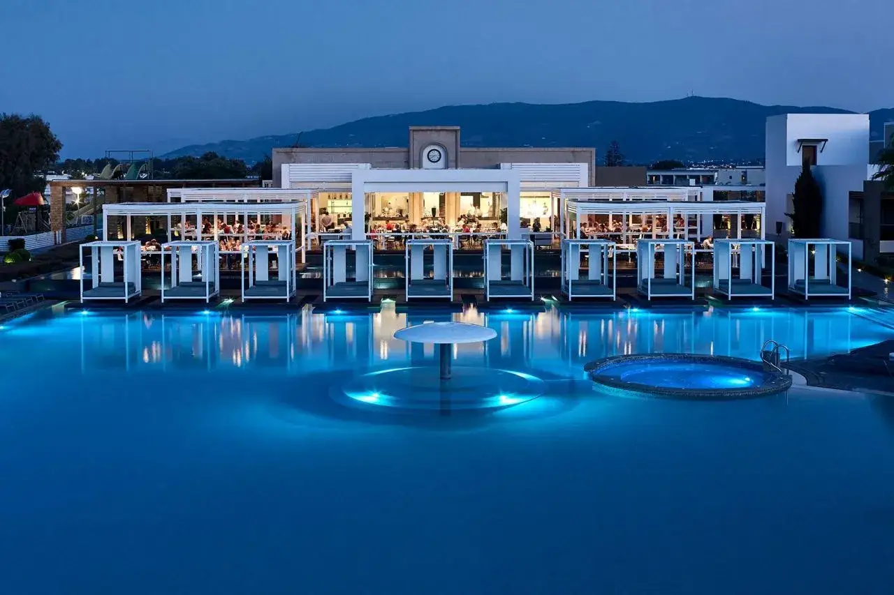 Abendstimmung am Pool des sentido pelagos suites & spa. Beleuchtete Cabanas und ein Whirlpool laden zum Entspannen ein.