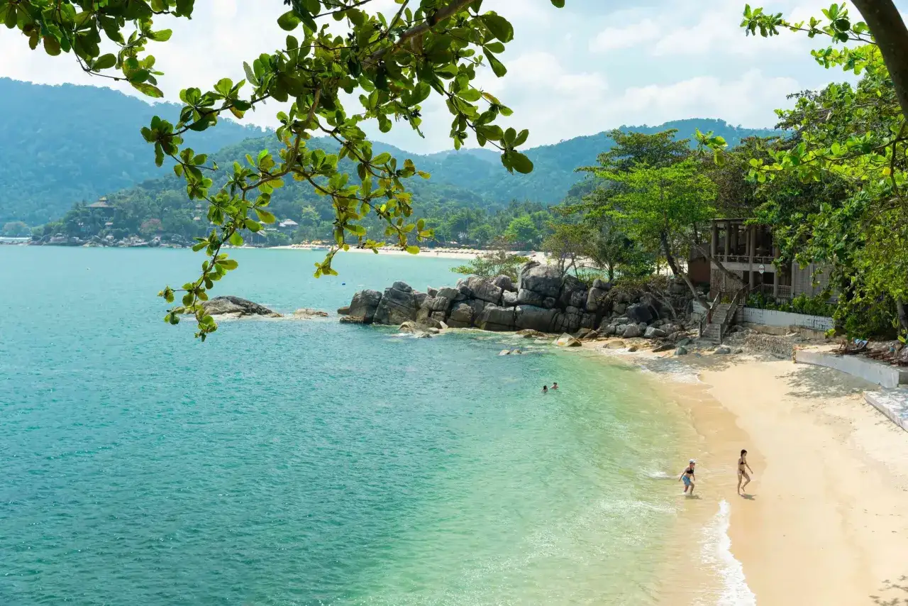 Traumhafte Bucht mit türkisfarbenem Wasser, Sandstrand und üppiger Vegetation. Perfekte Thailand Reisezeit für Entspannung und Badespaß.