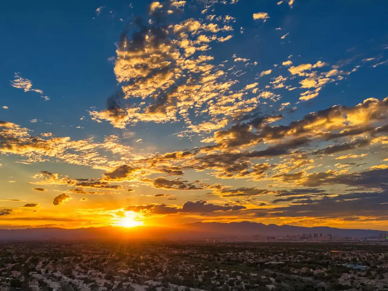Sonnenuntergang über Las Vegas. Goldene Wolken ziehen über den Himmel, während die Lichter der Stadt in der Ferne zu glühen beginnen.