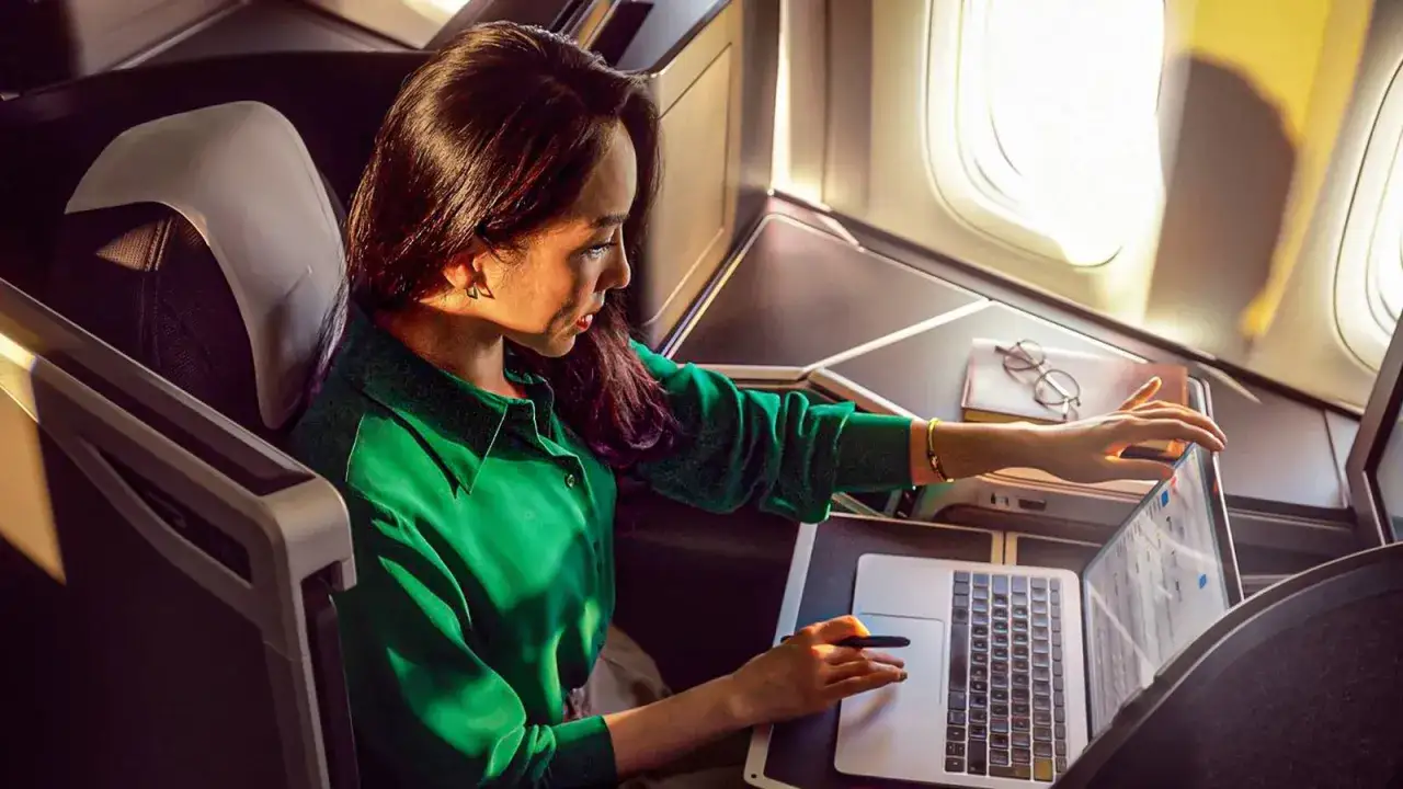 Frau arbeitet im Flugzeug mit Laptop. Ein kostenloses Upgrade Flug macht die Reise komfortabel.