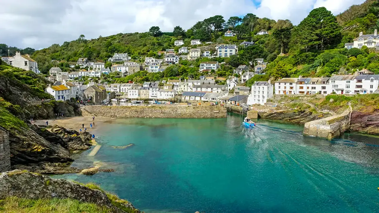 Idyllischer Hafenort in Cornwall, perfekt für einen England Urlaub. Weiße Häuser schmiegen sich an grüne Hügel, das türkisfarbene Wasser lädt zum Träumen ein.