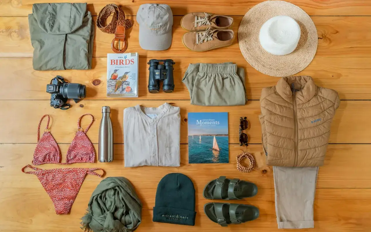 Die perfekte safari packliste: Kleidung, Kamera, Fernglas, Hut, Schuhe, Sonnenbrille und ein Buch &uuml;ber V&ouml;gel.
