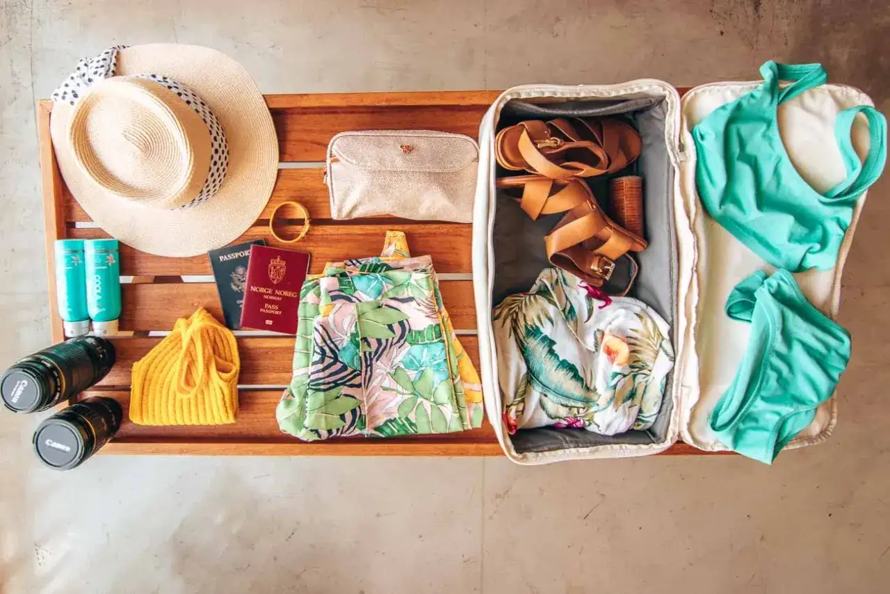Packliste für eine tropische Insel: Sonnenhut, Reisepässe, Badesachen, Sandalen und Kamera für unvergessliche Momente.