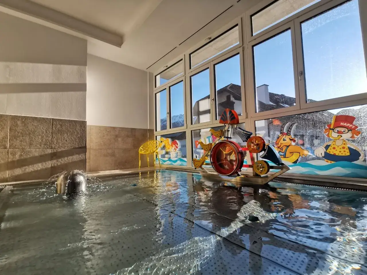 Spielerischer Pool im TUI Kids Club Alpina Tirol mit Wasserspielzeug und Bergpanorama.