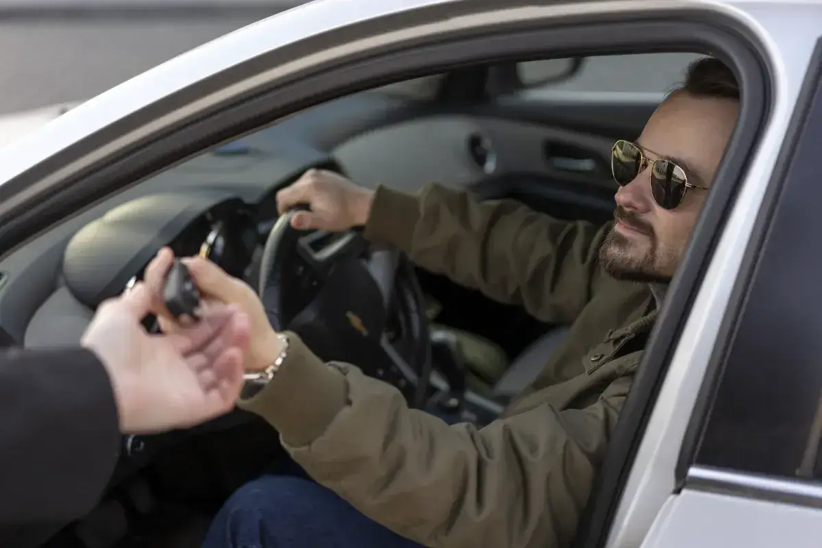 Mann im Auto gibt Schlüssel ab. Das ist, was valet bedeutet: jemand parkt Ihr Auto für Sie.