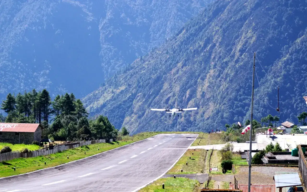 Flugzeug landet auf dem Lukla Airport, umgeben von steilen, bewaldeten Bergen.