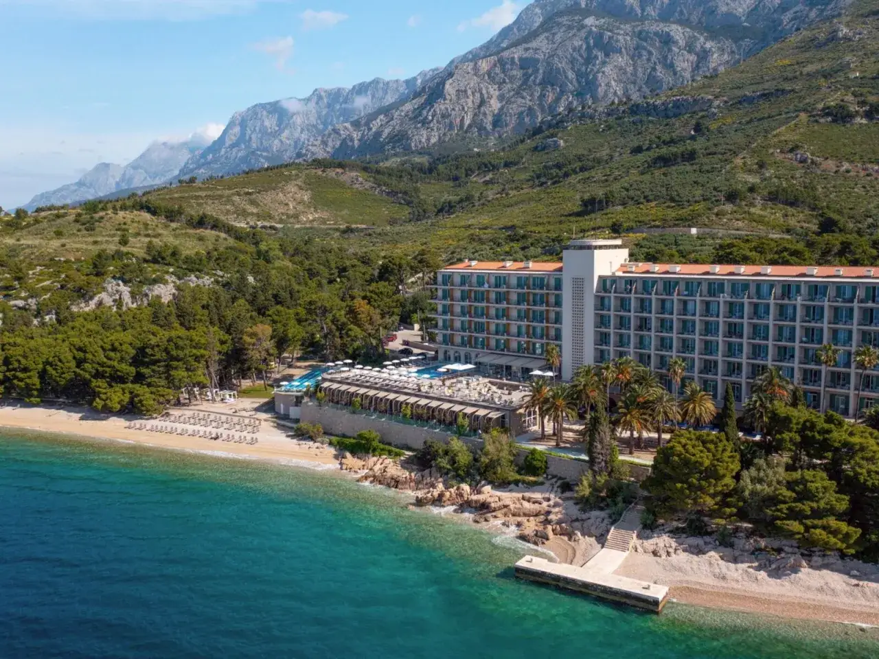 Traumhafter Blick auf das TUI Blue Jadran Hotel an der kroatischen Küste, mit türkisfarbenem Meer und Bergen im Hintergrund.