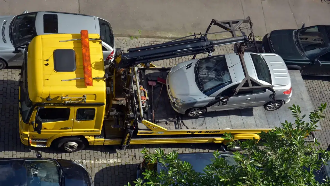Gelber Abschleppwagen lädt silbernes Auto auf. Der Fahrer des silbernen Autos ist sicher zu unrecht abgeschleppt worden.