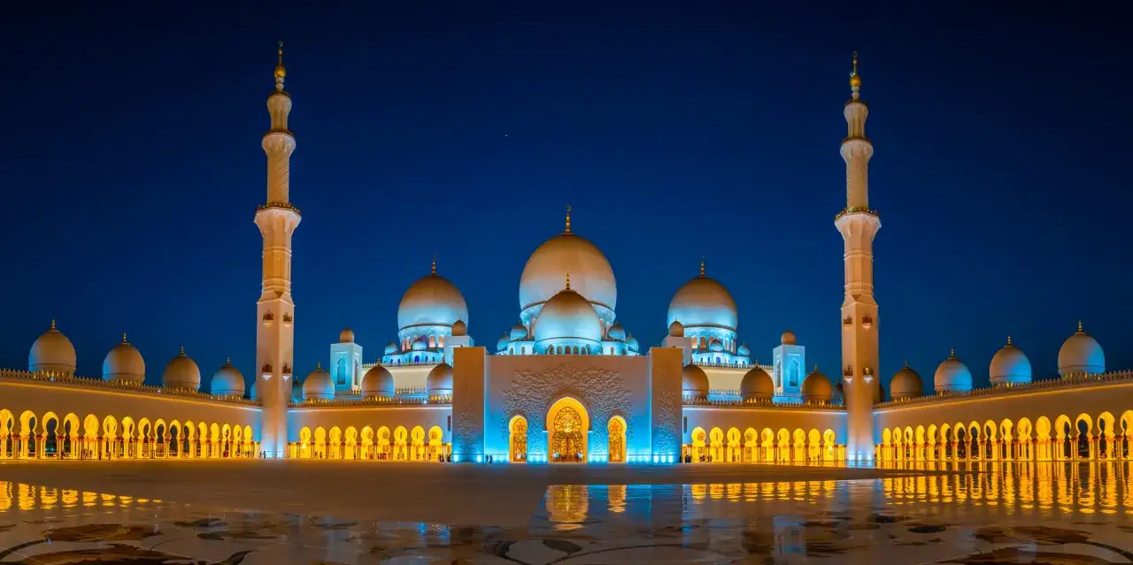 Die Sheikh-Zayid-Moschee in Abu Dhabi erstrahlt nachts in blauem und goldenem Licht.