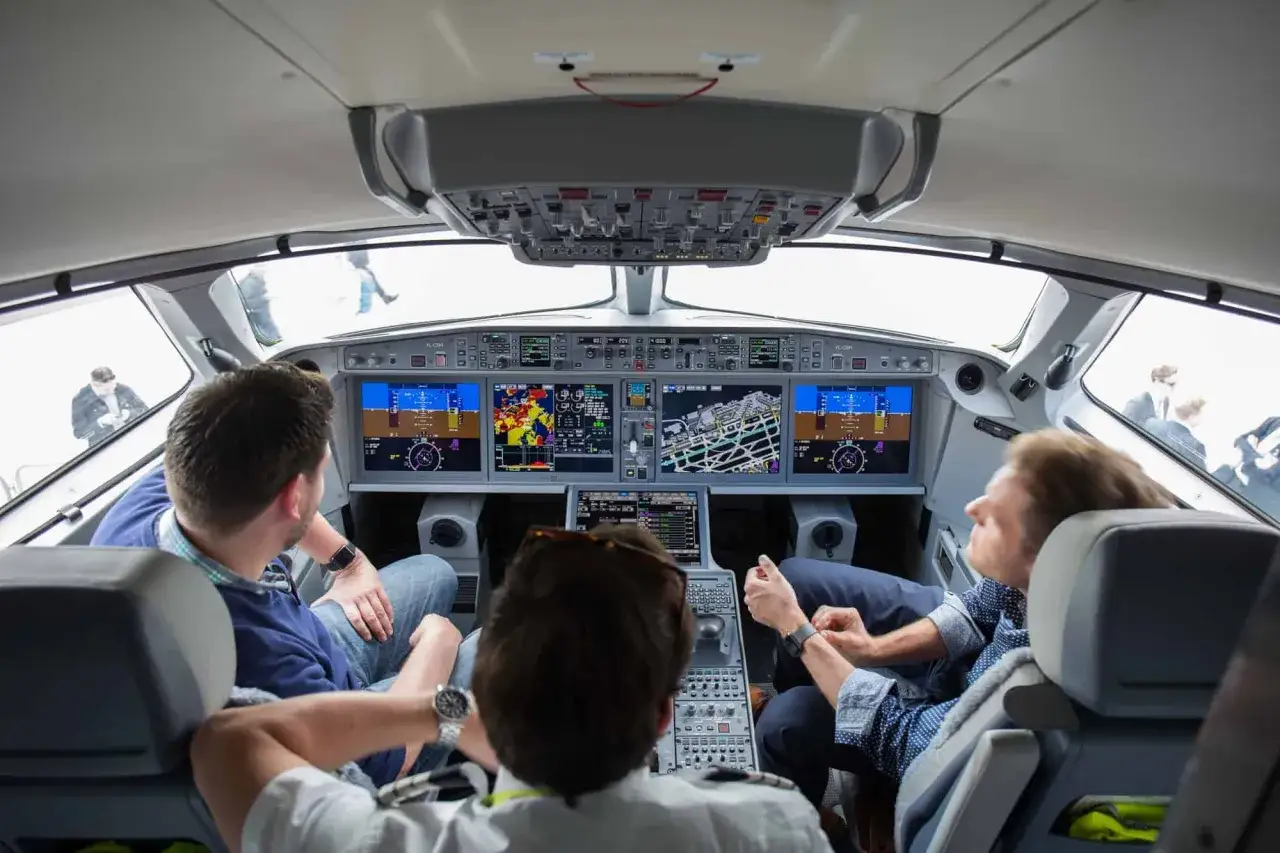 Blick ins Cockpit: Ein Pilot, der wie ein deadhead pilot aussieht, sitzt mit zwei anderen Männern vor den Bildschirmen.