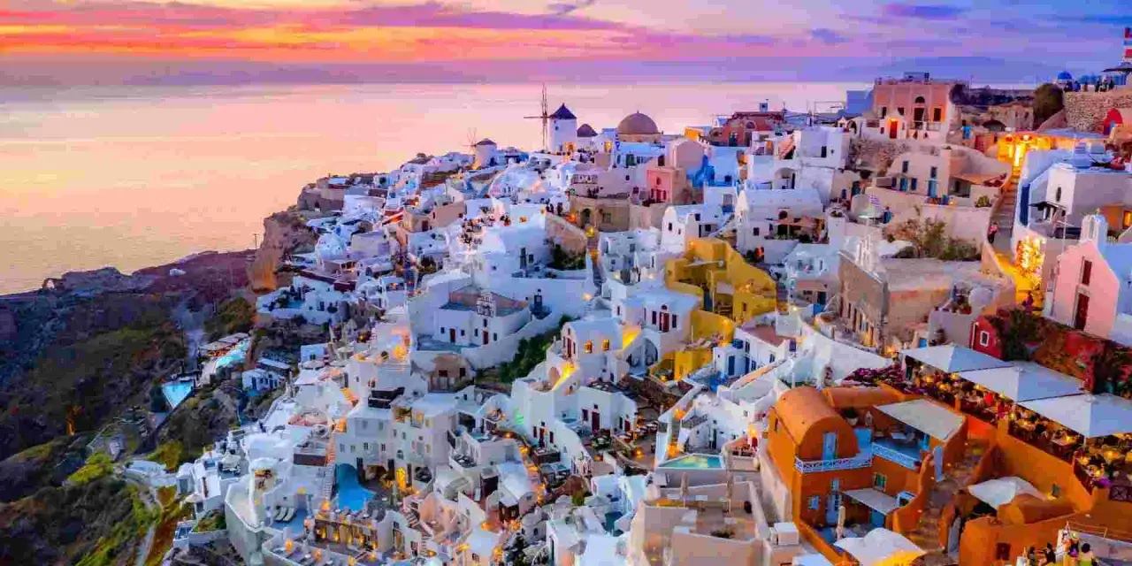 Traumhafter Santorin Urlaub: Weiße Häuser schmiegen sich an den Hang, Windmühlen und das Meer im Abendrot. Ein unvergesslicher Anblick.