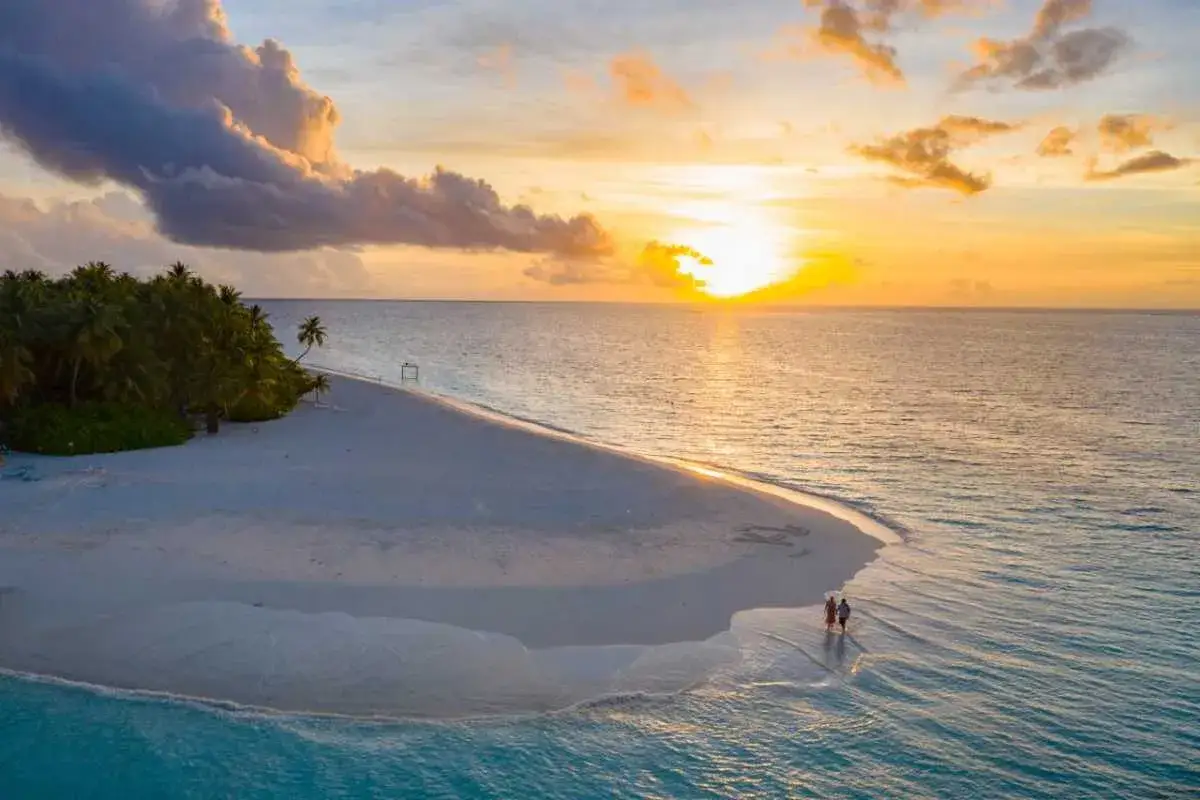 Traumpaar spaziert am Strand bei Sonnenuntergang. Perfekt für die beste Reisezeit Mauritius.