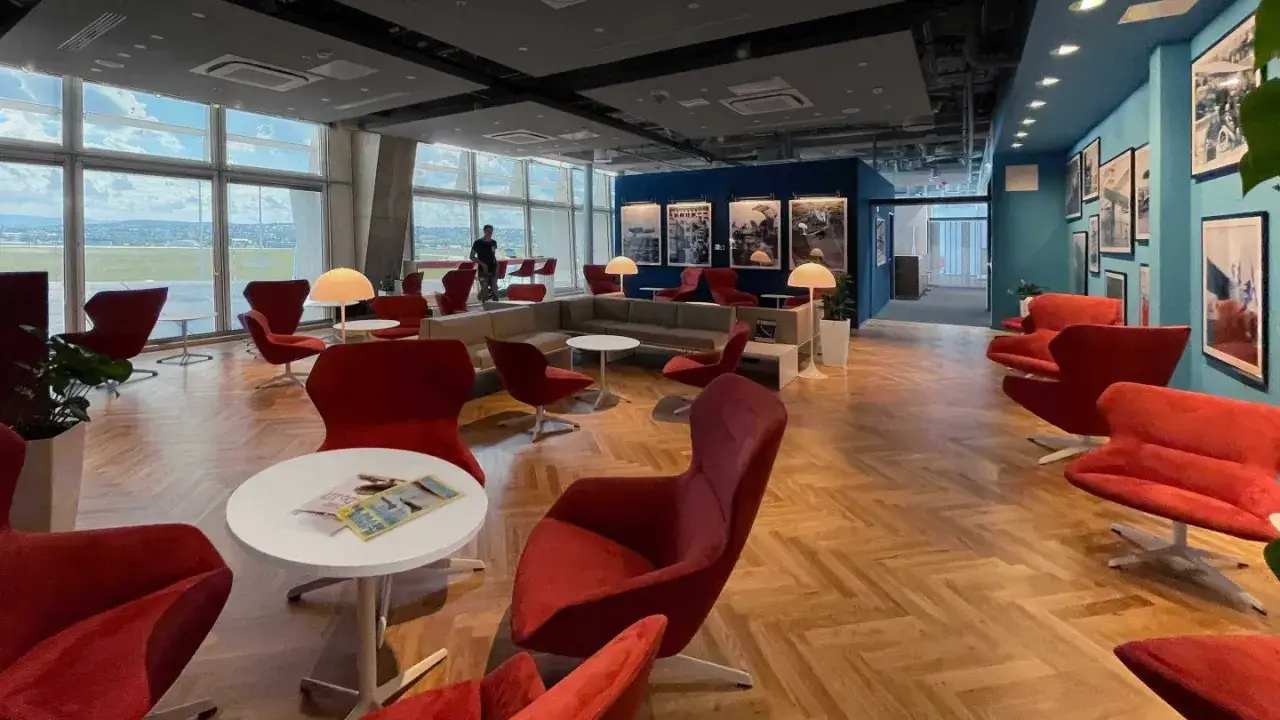 Gemütliche Lounge mit roten Sesseln und Blick auf das Flugfeld. Perfekt für einen entspannten Priority Pass Stuttgart.