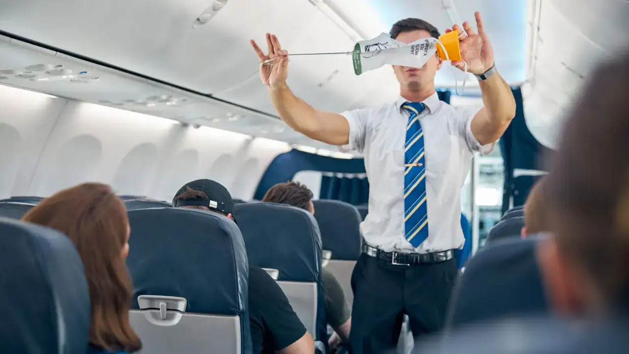 Stewardess demonstriert Sauerstoffmaske an Bord. Ein wichtiger Teil des Stewardess Jobs ist die Sicherheit der Passagiere.