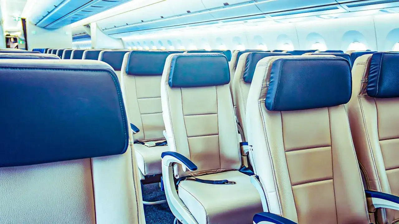 Leere Flugzeugsitze in Beige und Dunkelblau. Die Sitze sind für einen ab wann langstreckenflug vorbereitet.
