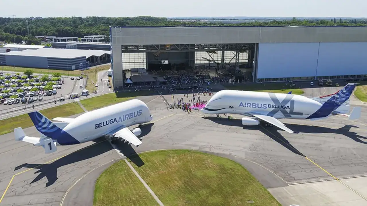 Zwei Airbus Beluga Flugzeuge stehen nebeneinander vor einer großen Halle.