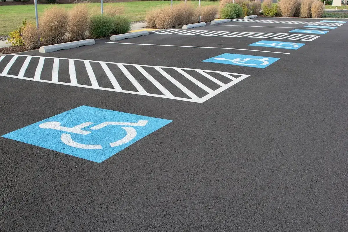 Reihe von blau markierten Stellplätzen mit Rollstuhlsymbolen. Ein parkplatz behindertengerecht, bereit für Besucher.