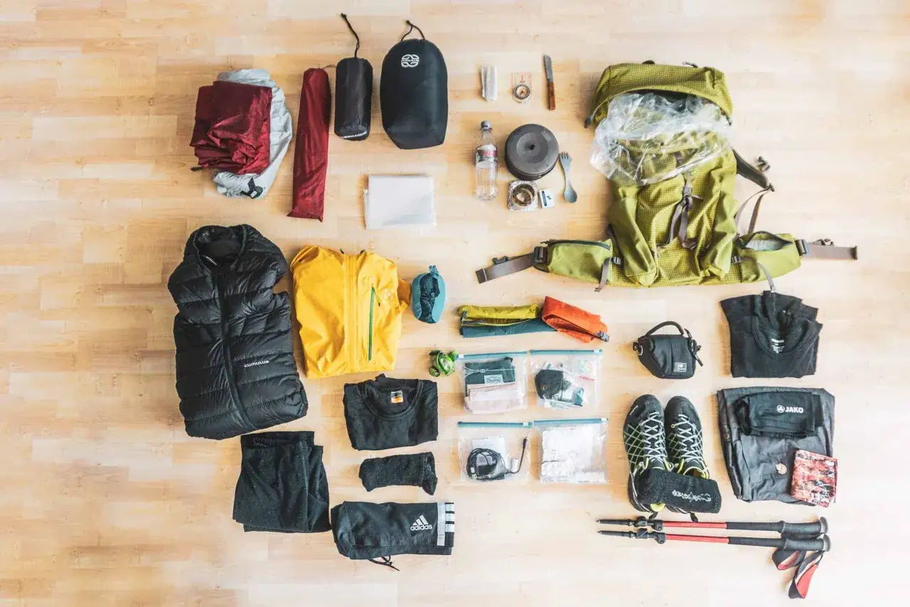 Packliste Bergtour: Rucksack, Zelt, Schlafsack, Daunenjacke, Funktionskleidung, Wanderschuhe, Trekkingstöcke, Kochutensilien, Erste-Hilfe-Set und mehr.