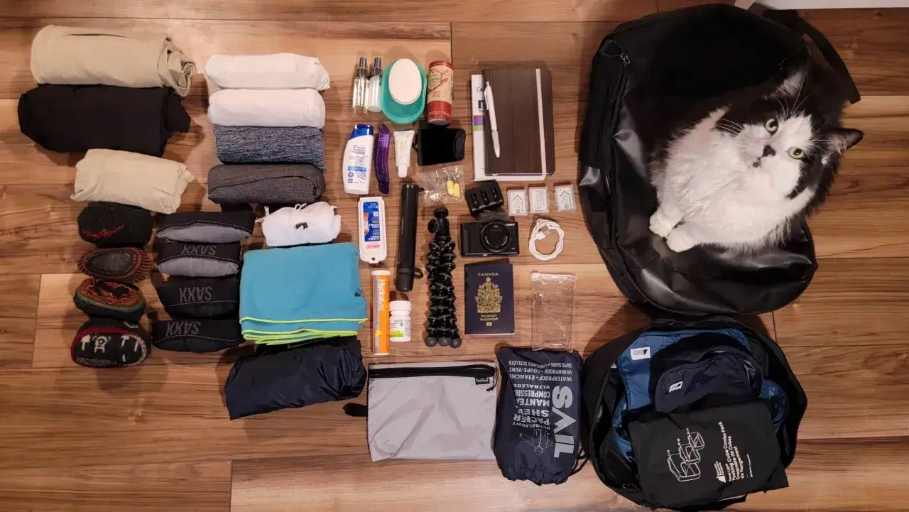 Neuseeland Kleidung und Reiseutensilien sind bereit für das Abenteuer. Ein flauschiger Reisebegleiter wacht über den Rucksack.