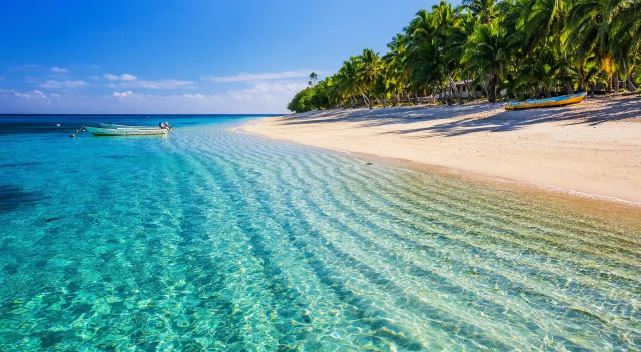 Traumhafter Fidschi Urlaub: Türkisblaues Wasser, weißer Sandstrand mit Palmen und Boote. Perfekt für Entspannung.