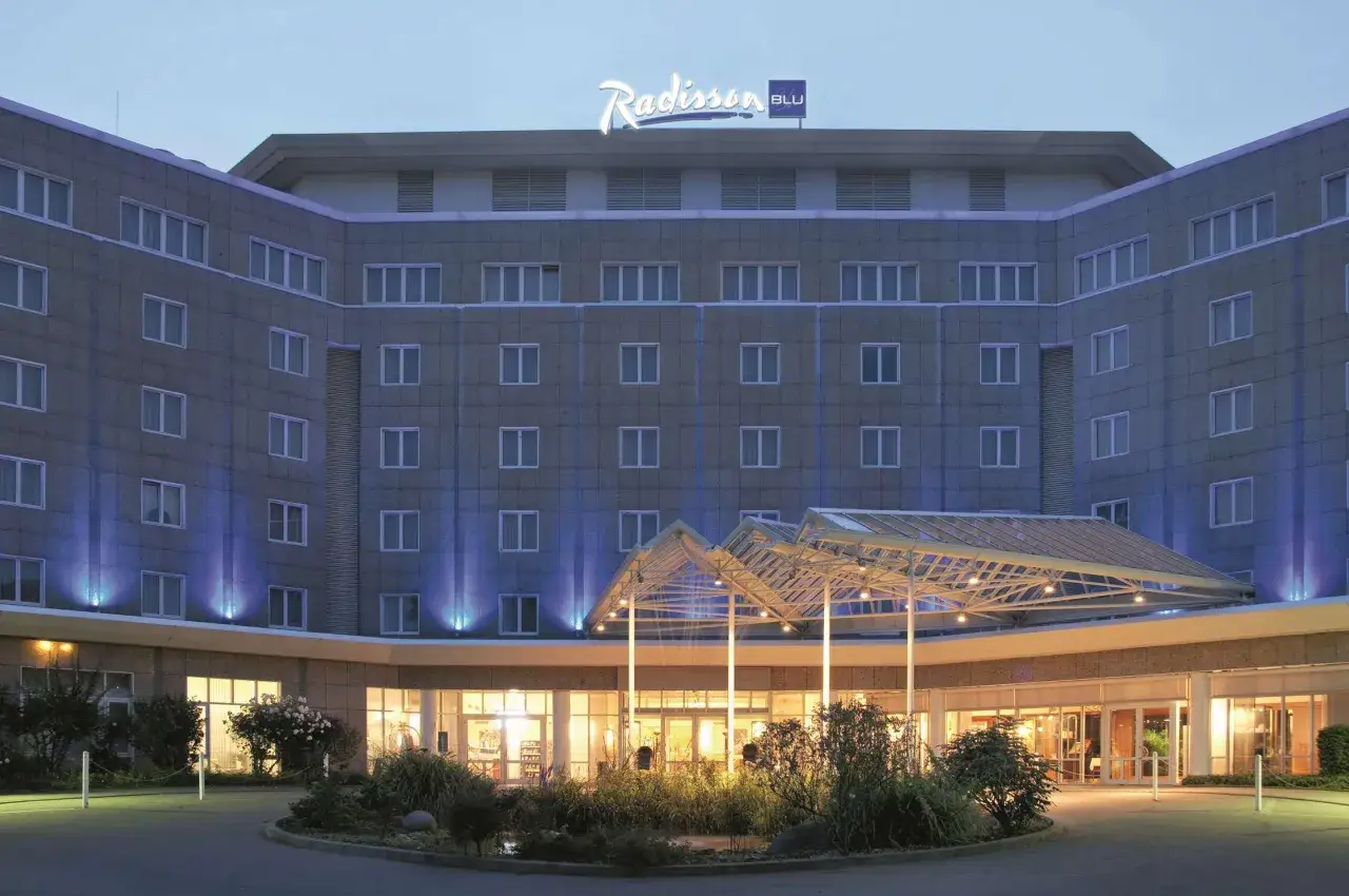 Das Radisson Blu Dortmund bei Nacht, mit beleuchtetem Eingangsbereich und blauen Akzenten an der Fassade.