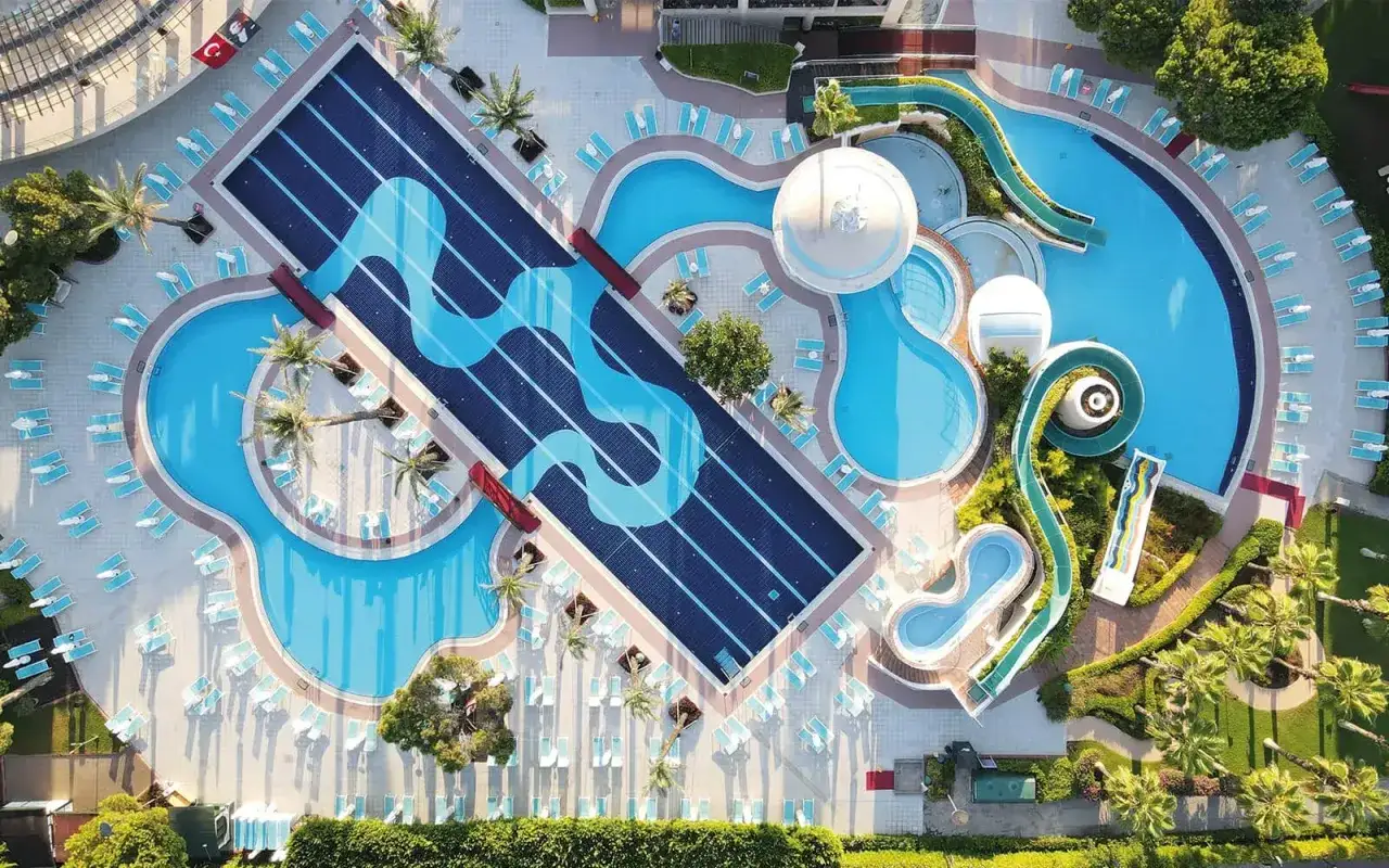 Luftaufnahme des Limak Atlantis De Luxe Hotel & Resort mit Pools, Wasserrutschen und Liegestühlen.