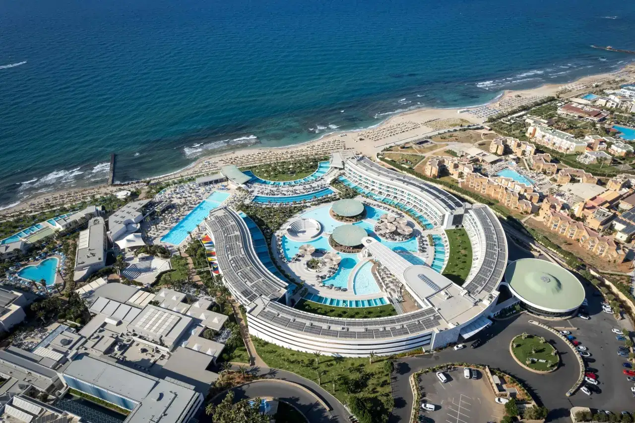 Luxuriöses Resort am Lyttos Mare Kreta mit geschwungenen Gebäuden, Pools und Blick auf das türkisfarbene Meer.