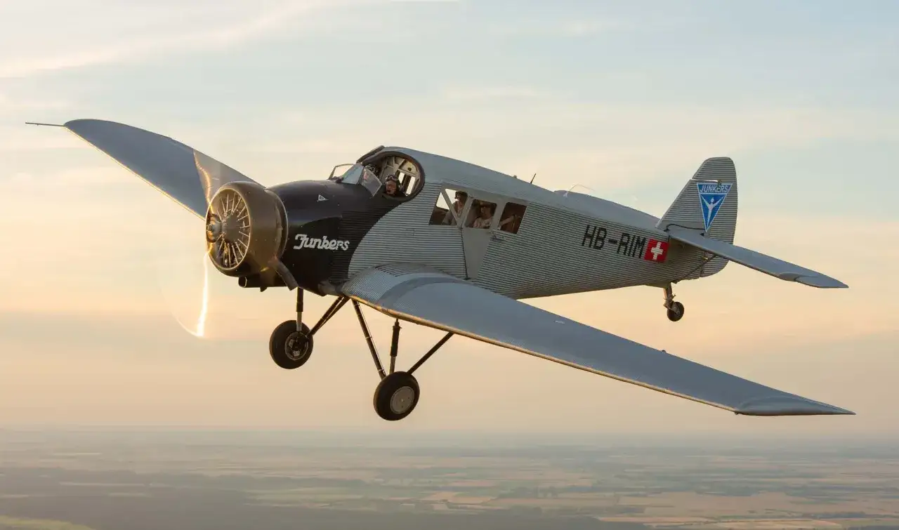 Junkers F 13, das erste passagierflugzeug deutschland, fliegt im Abendlicht über die Landschaft.