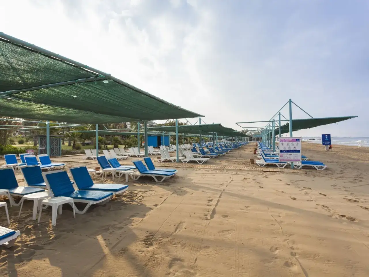 Reihen von Liegestühlen unter grünen Sonnensegeln am IZI Flower Side Beach.