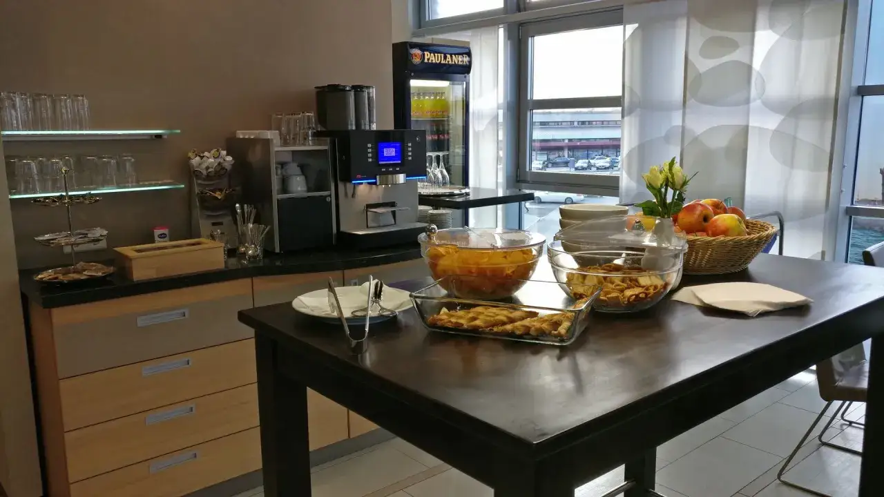 Snacks und Getränke in der Priority Pass Lounge Berlin. Obst, Gebäck und eine Kaffeemaschine stehen bereit.