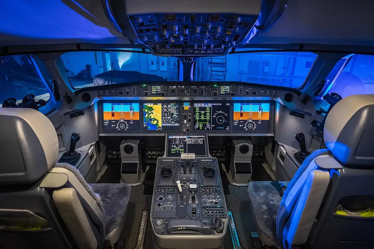 Das Cockpit eines Flugzeugs, ein komplexer Arbeitsplatz mit Bildschirmen, Knöpfen und Hebeln, bereit für den Flug.