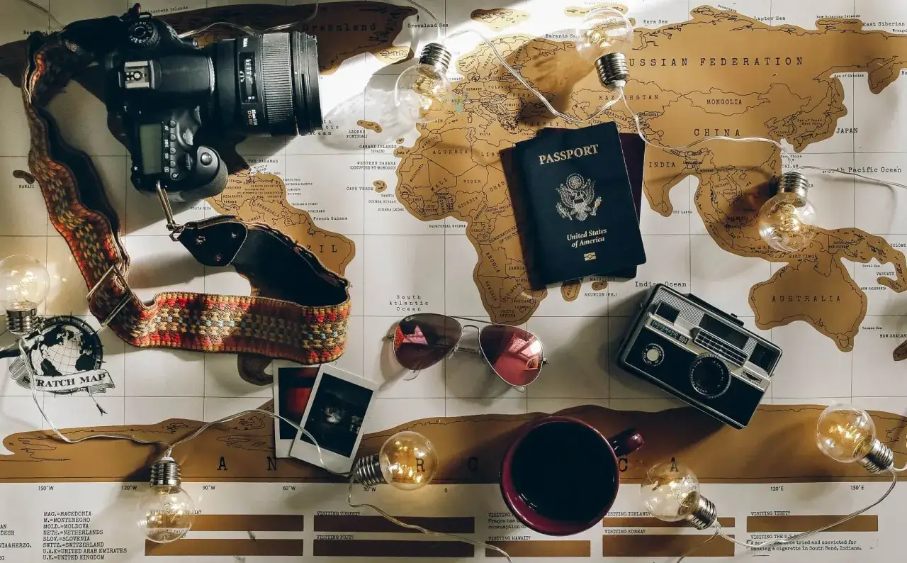 Reiseutensilien für Kenia: Kamera, Reisepass, Sonnenbrille, alte Fotos und eine Tasse. Packliste für Abenteuer!