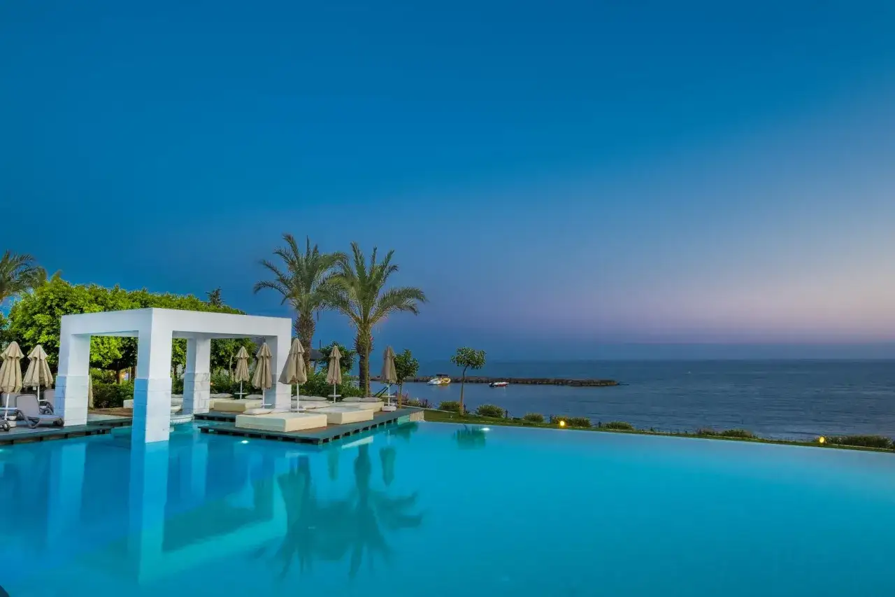 Infinity-Pool mit Palmen und einem Pavillon am Abend. Ein Traumurlaub im Mary Hotel Alanya.