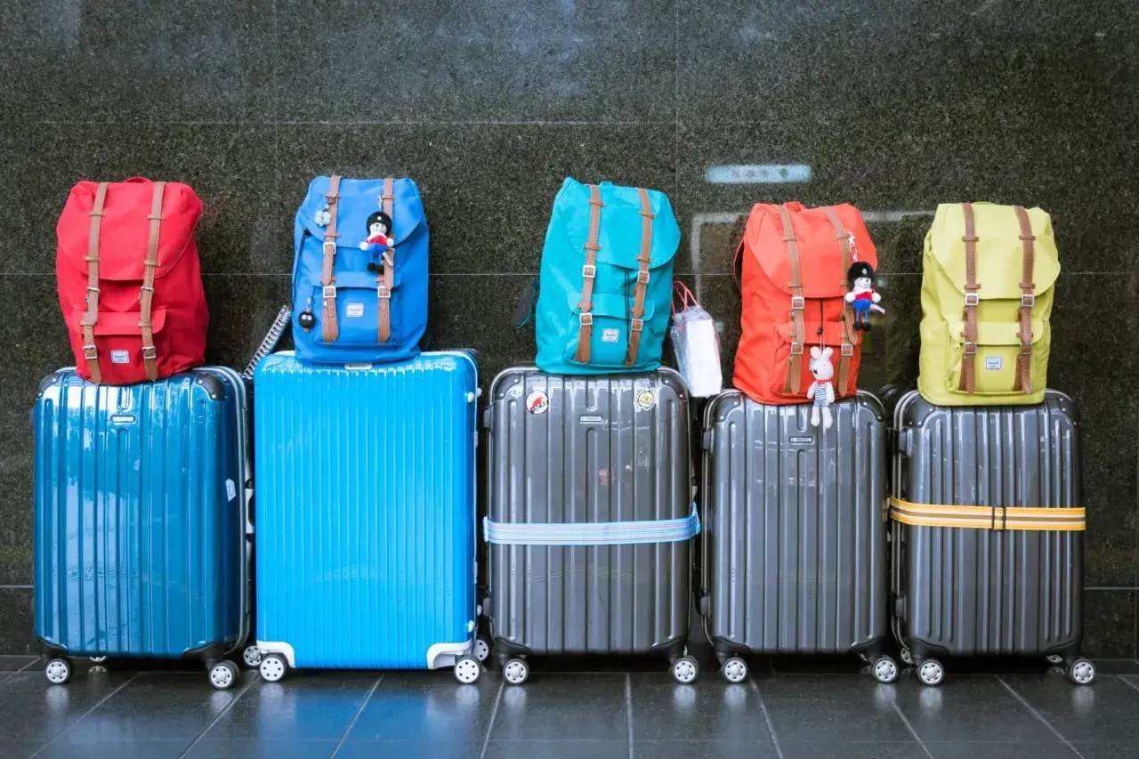 Reisekoffer und Rucksäcke in bunten Farben, bereit für ein Auslandssemester. Die perfekte Ausrüstung für deine Auslandssemester Packliste.