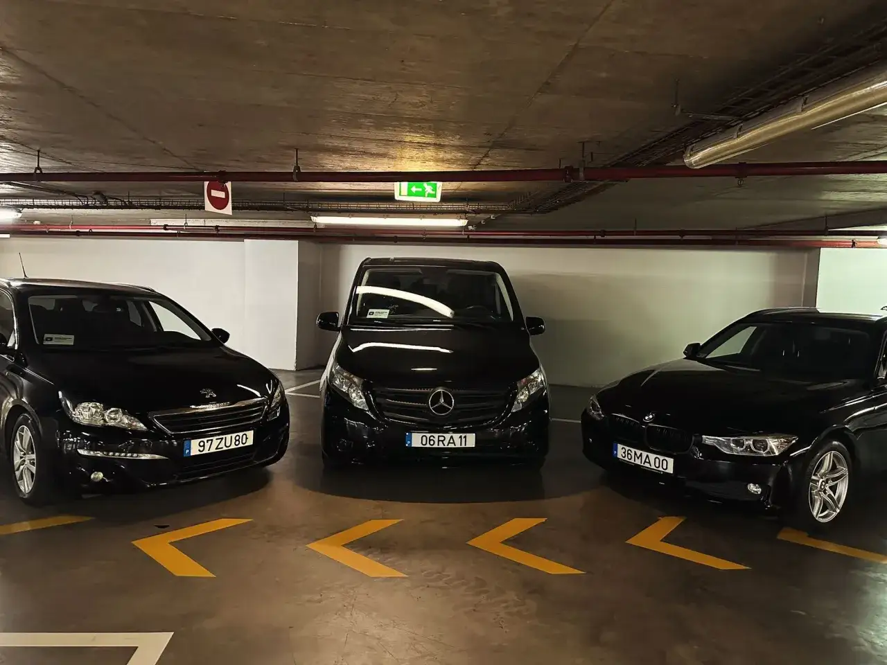 Drei schwarze Autos, ein Mercedes-Van in der Mitte, stehen in einer Tiefgarage am Madeira Flughafen.