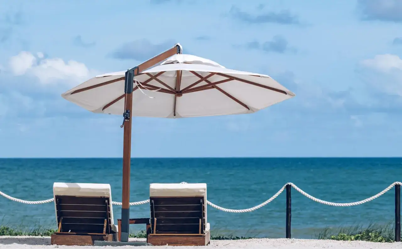 Zwei Liegestühle unter einem Sonnenschirm am Strand. Perfekt für die Packliste Brasilien: Badesachen, Sonnencreme und ein gutes Buch.
