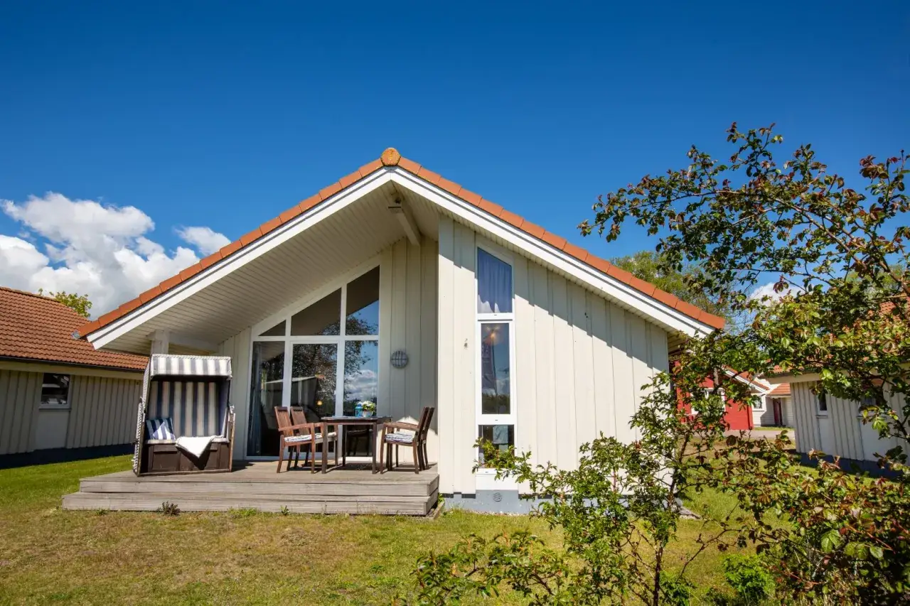 Gemütliches Ferienhaus mit Strandkorb und Tisch auf der Terrasse. Perfekt für einen Urlaub mit Hund am Meer.