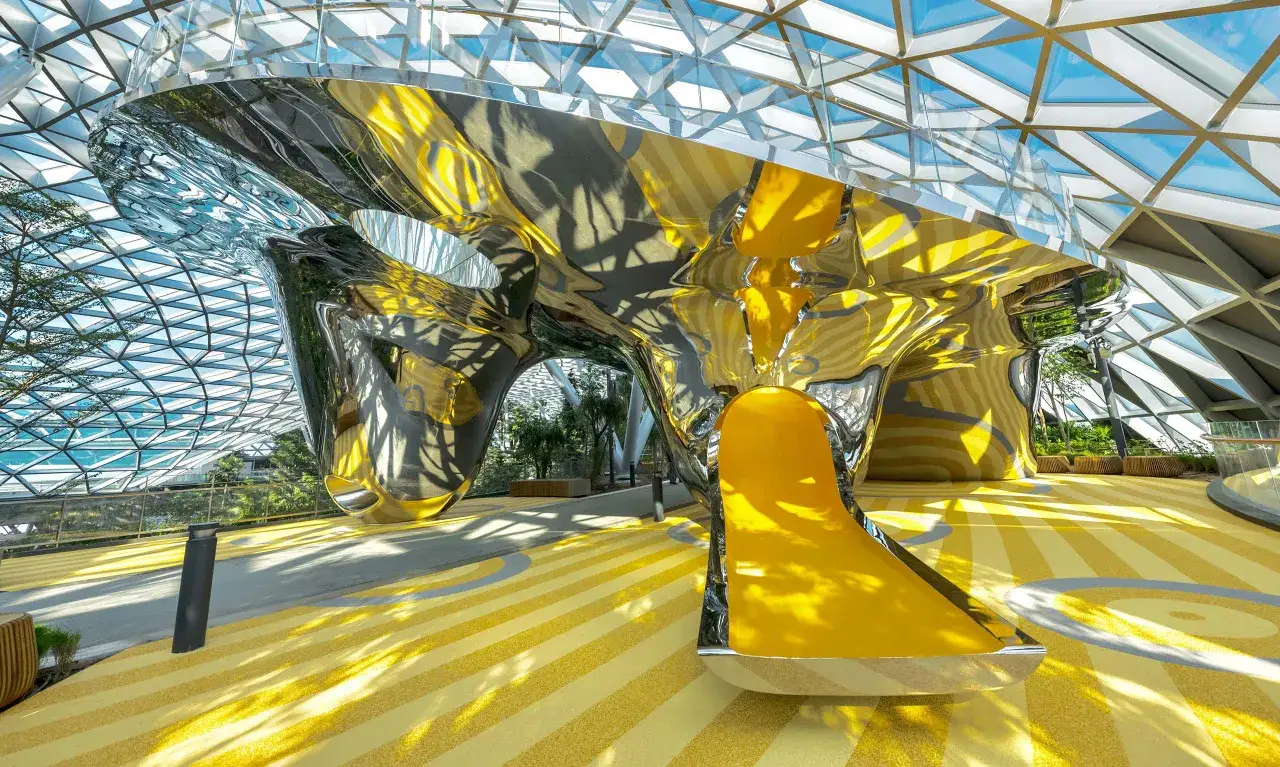 Futuristische Rutsche im Singapur Flughafen Jewel, mit glänzender, metallischer Struktur und gelben Akzenten.