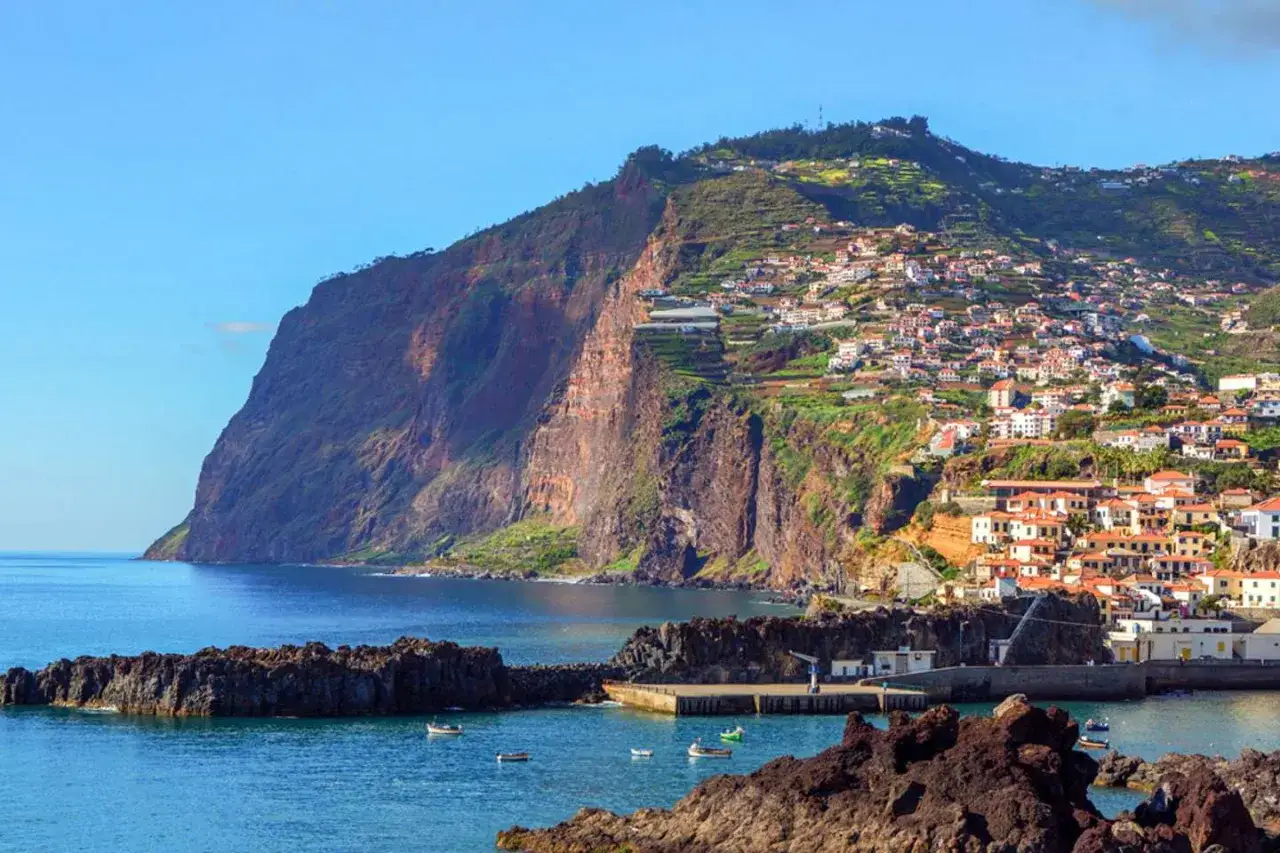 Bunte Häuser schmiegen sich an steile Hänge über dem Meer. Perfekt für die beste Reisezeit Madeira, wenn die Sonne scheint.