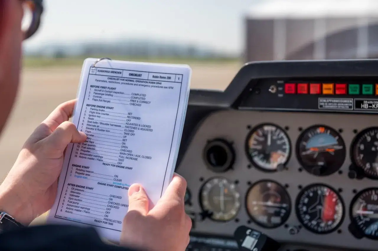 Pilot prüft Checkliste für die Flugzeug Kontrolle. Instrumente im Cockpit sind sichtbar.