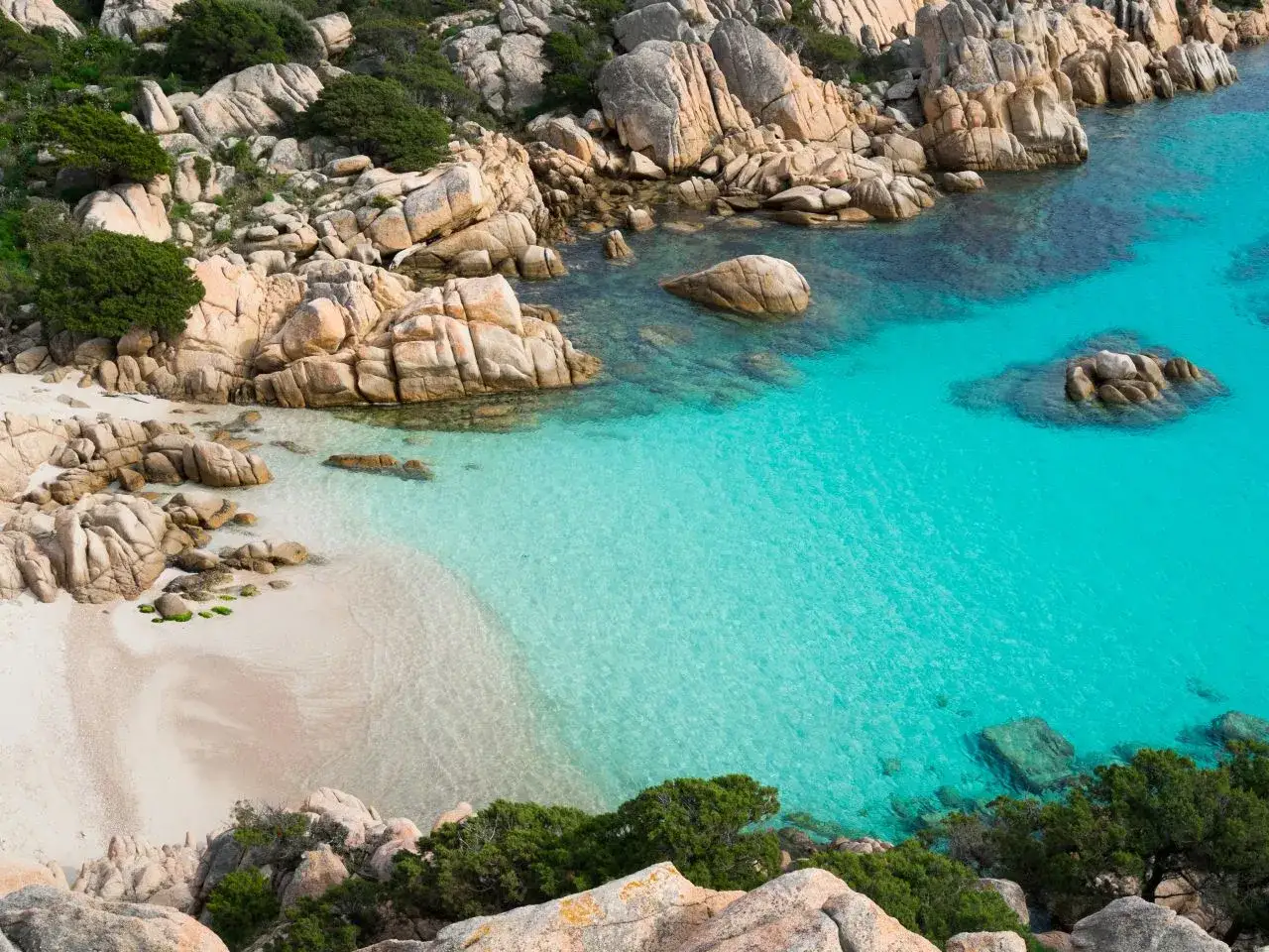 Traumhafter Urlaub in Italien: Türkises Meer umspült eine kleine Bucht mit Sandstrand und Felsen.