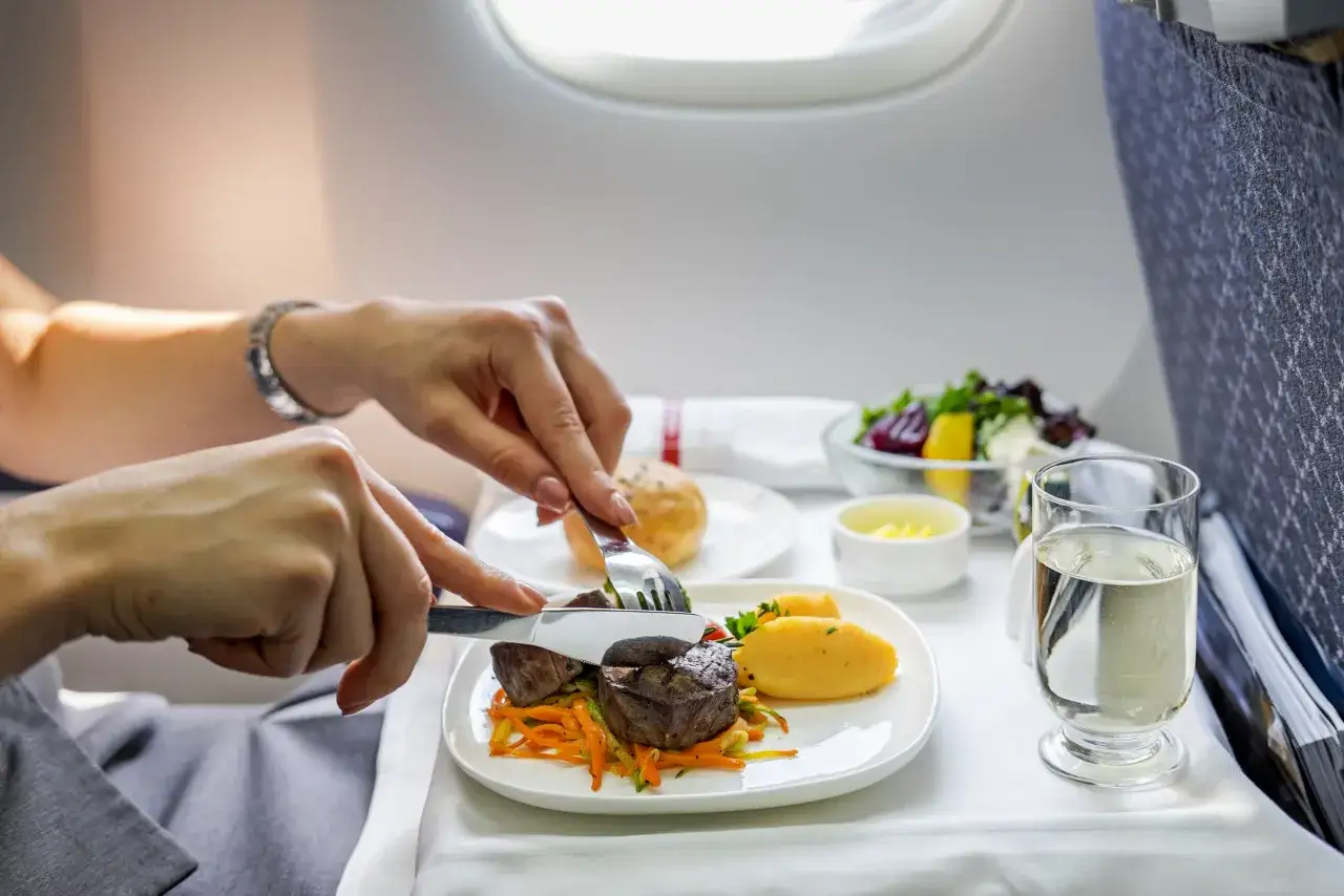 Genussvolles tuifly essen: Ein zartes Steak mit Kartoffelpüree und Gemüse, dazu ein Salat und ein Glas Wasser.