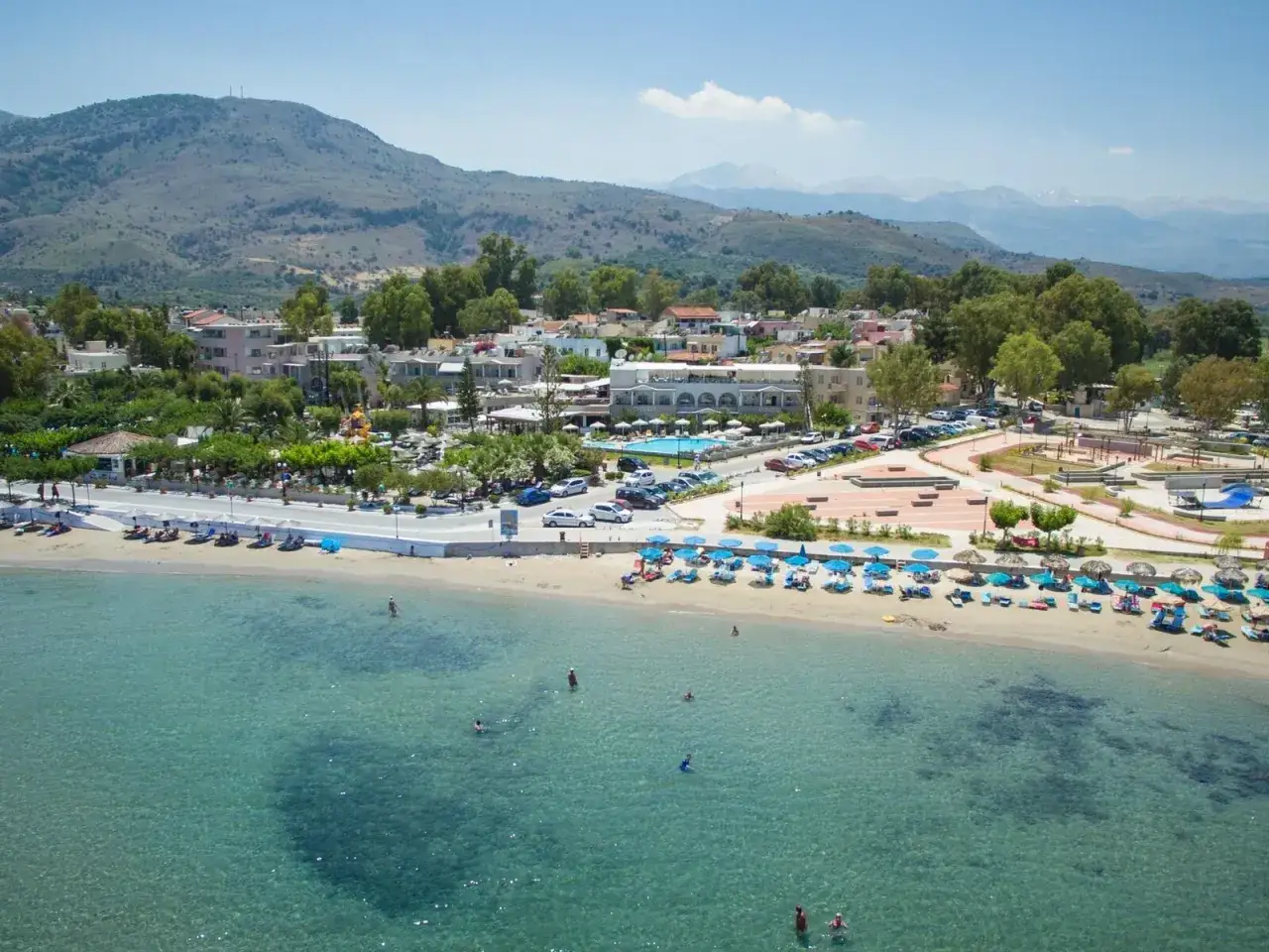 Ein epos luxury beach hotel mit Pool und vielen Liegen am Sandstrand, umgeben von gr&uuml;nen H&uuml;geln und blauem Meer.