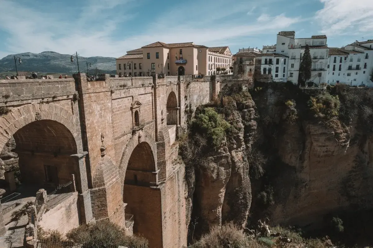 Majestätische Brücke in Ronda, Spanien, überspannt eine tiefe Schlucht. Weiße Häuser klammern sich an die Felsen.