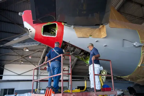 Zwei Mechaniker auf einer Hebebühne arbeiten am Triebwerk eines Flugzeugs. Ein wichtiger Begriff aus der Fliegerei wird hier greifbar.