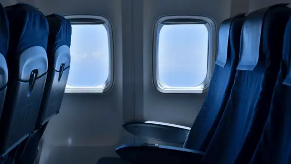 Leere Flugzeugsitze mit Blick auf den blauen Himmel. Eine Sitzplatzreservierung im Flugzeug ist sinnvoll, um den besten Platz zu sichern.