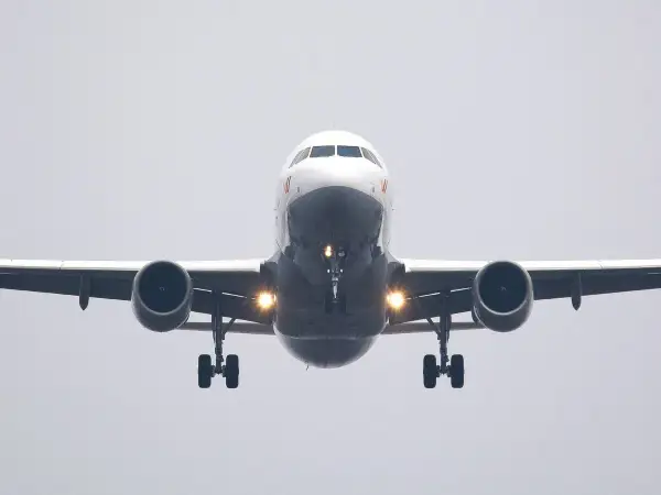 Ein Flugzeug nähert sich mit hoher Geschwindigkeit der Landebahn. Die Lichter am Fahrwerk leuchten hell.